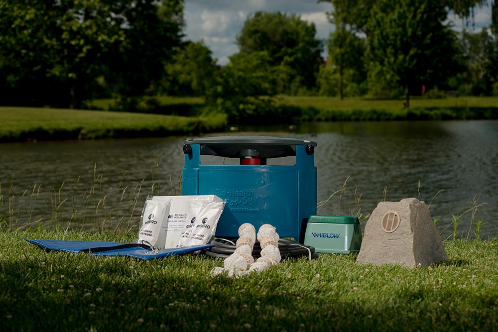 Learn about Rigero’s patented Bio-Health Pod system equipment displayed pondside for natural water restoration.